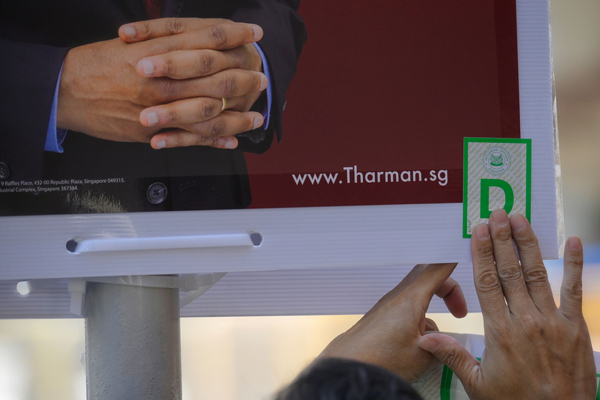 A man putting up a campaign poster with the stamp of the Returning Officer for Mr Tharman at a block of flats in Jalan Besar on Aug 22, 2023. ST PHOTO: MARK CHEONG