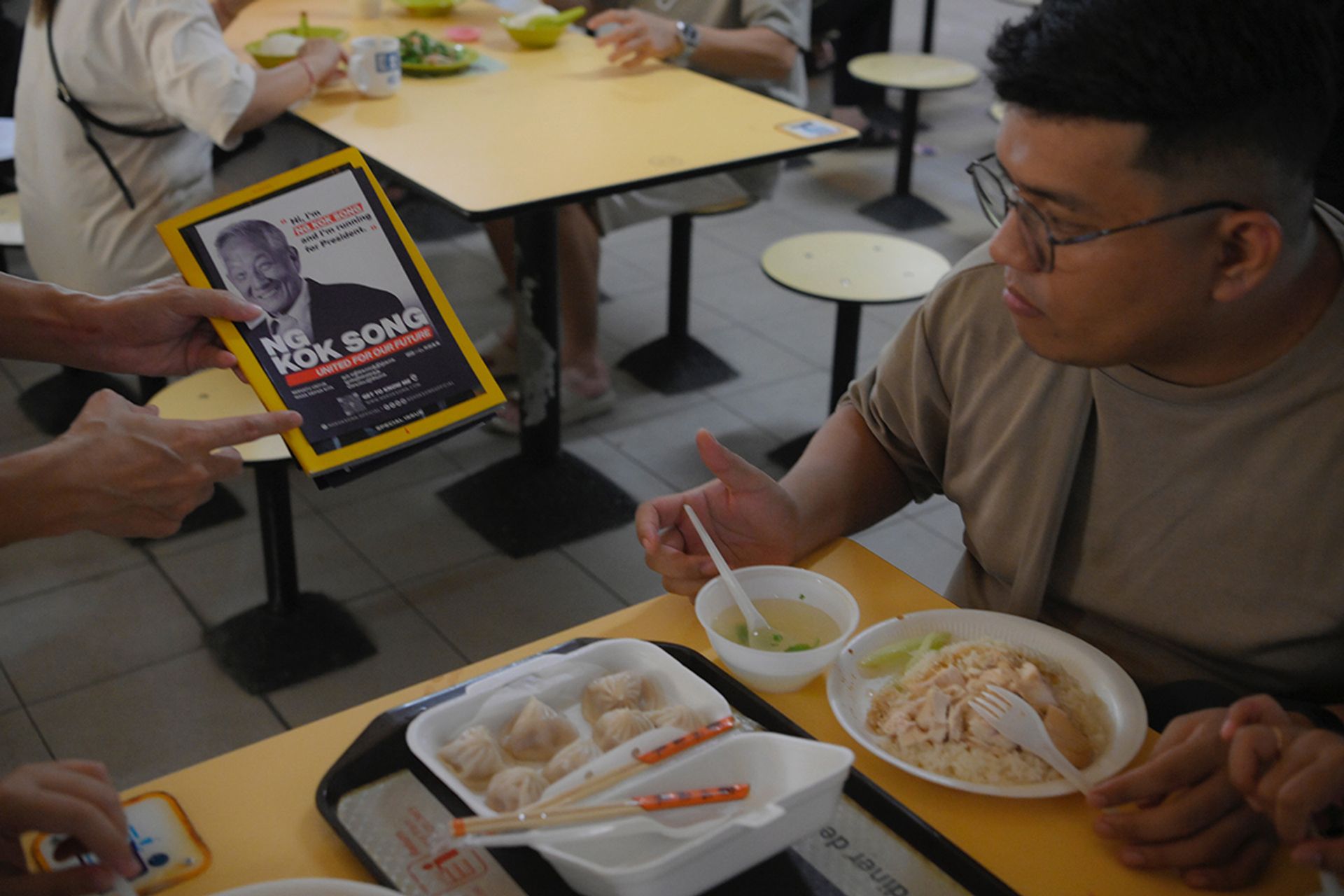 A volunteer with Mr Ng’s team hands out flyers to patrons at Chinatown Complex Market and Food Centre during a walkabout on Aug 27, 2023. ST PHOTO: MARK CHEONG