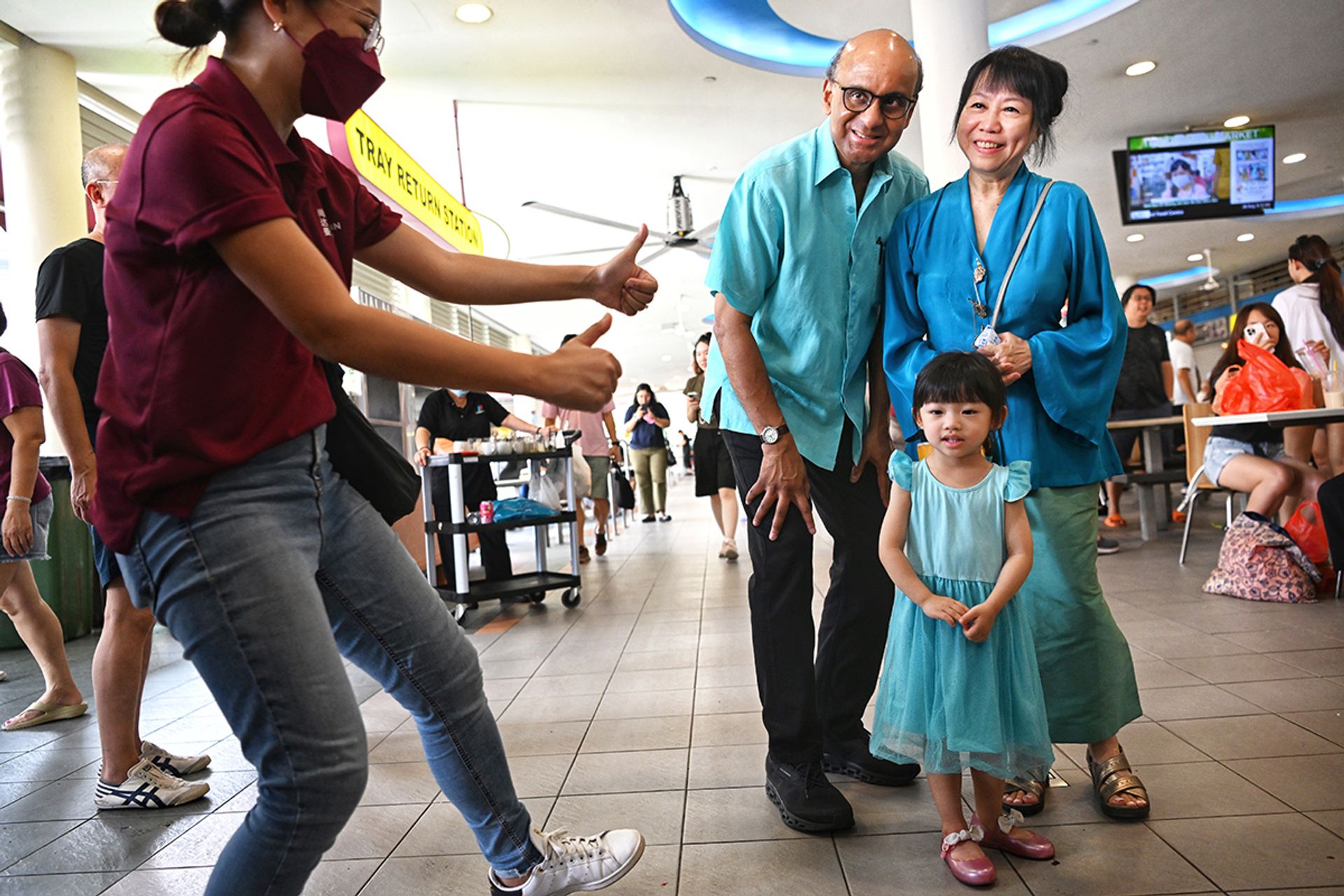 A campaign staff member coaxing a smile from three-year-old Clovelly Foo during photo taking with Mr Tharman and his wife at Tiong Bahru market on Aug 26, 2023. ST PHOTO: CHONG JUN LIANG