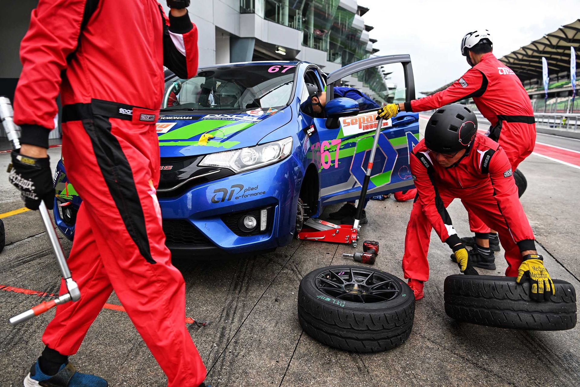 Volunteer mechanics changing the front tyres of the No. 67 Honda Jazz, one of three Team 667 cars in the annual race.